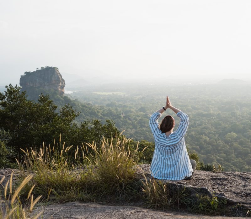 Woman doing yoga at sunset with scenic view Sigiriya in Sri Lanka